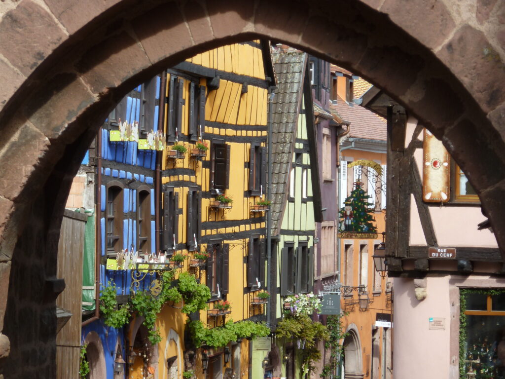 Colourful half-timbered houses of Riquewihr framed through a medieval stone arch on a luxury Christmas wine tour in Alsace, France