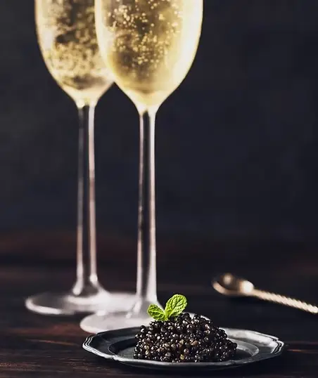 Two elegant champagne flutes with caviar on a silver plate, luxury wine and gourmet dining experience in France