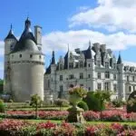 Château de Chenonceau with its round Tour des Marques tower and formal pink flower gardens under a blue sky, Loire Valley France
