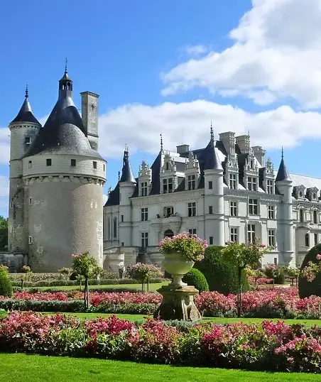 Château de Chenonceau with its round Tour des Marques tower and formal pink flower gardens under a blue sky, Loire Valley France