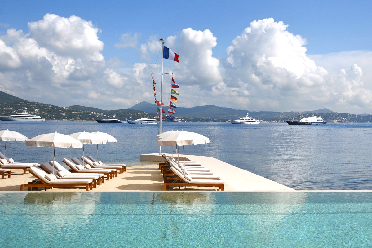 Cheval Blanc St-Tropez infinity pool with sun loungers, white umbrellas and superyachts on the Mediterranean, French Riviera, France