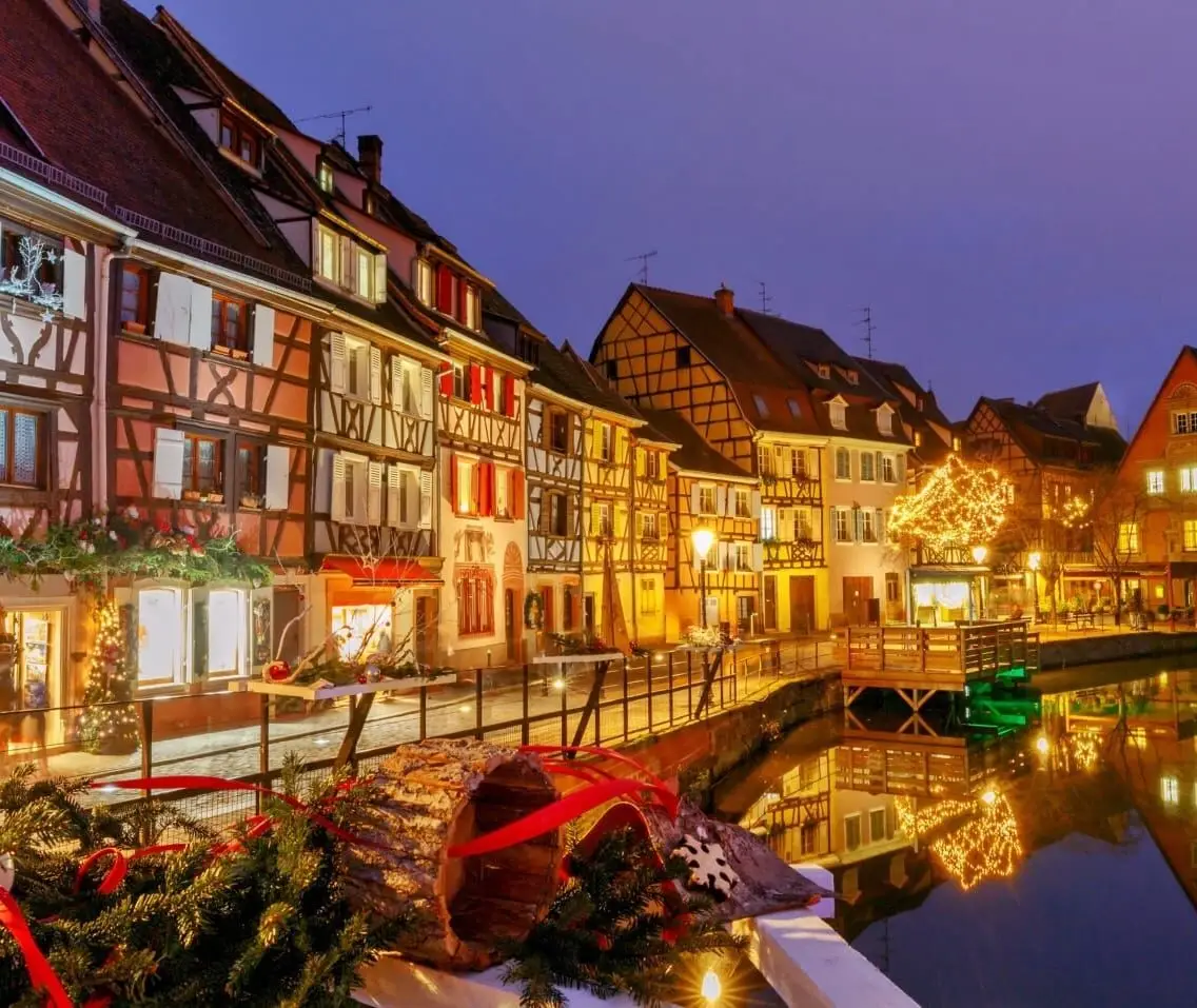 Colmar Little Venice canal at night with Christmas lights, decorated half-timbered houses reflected in water, Alsace, France