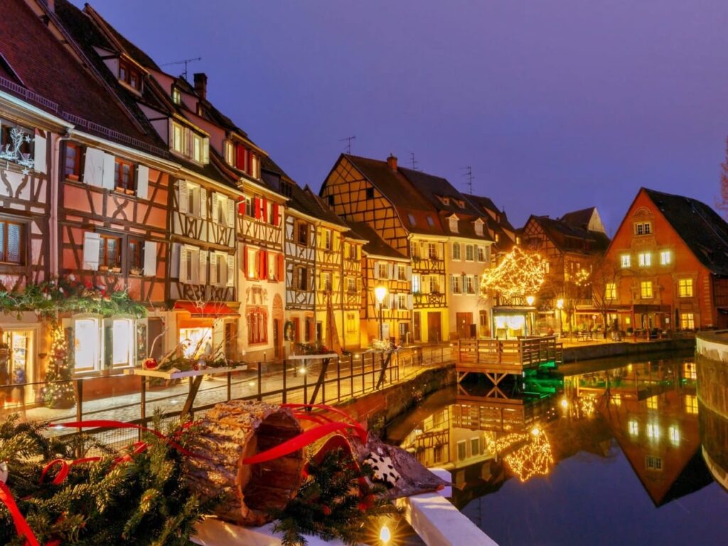 Colmar Little Venice canal at twilight with Christmas lights and festive decorations reflected in still water, luxury Christmas wine tour Alsace, France