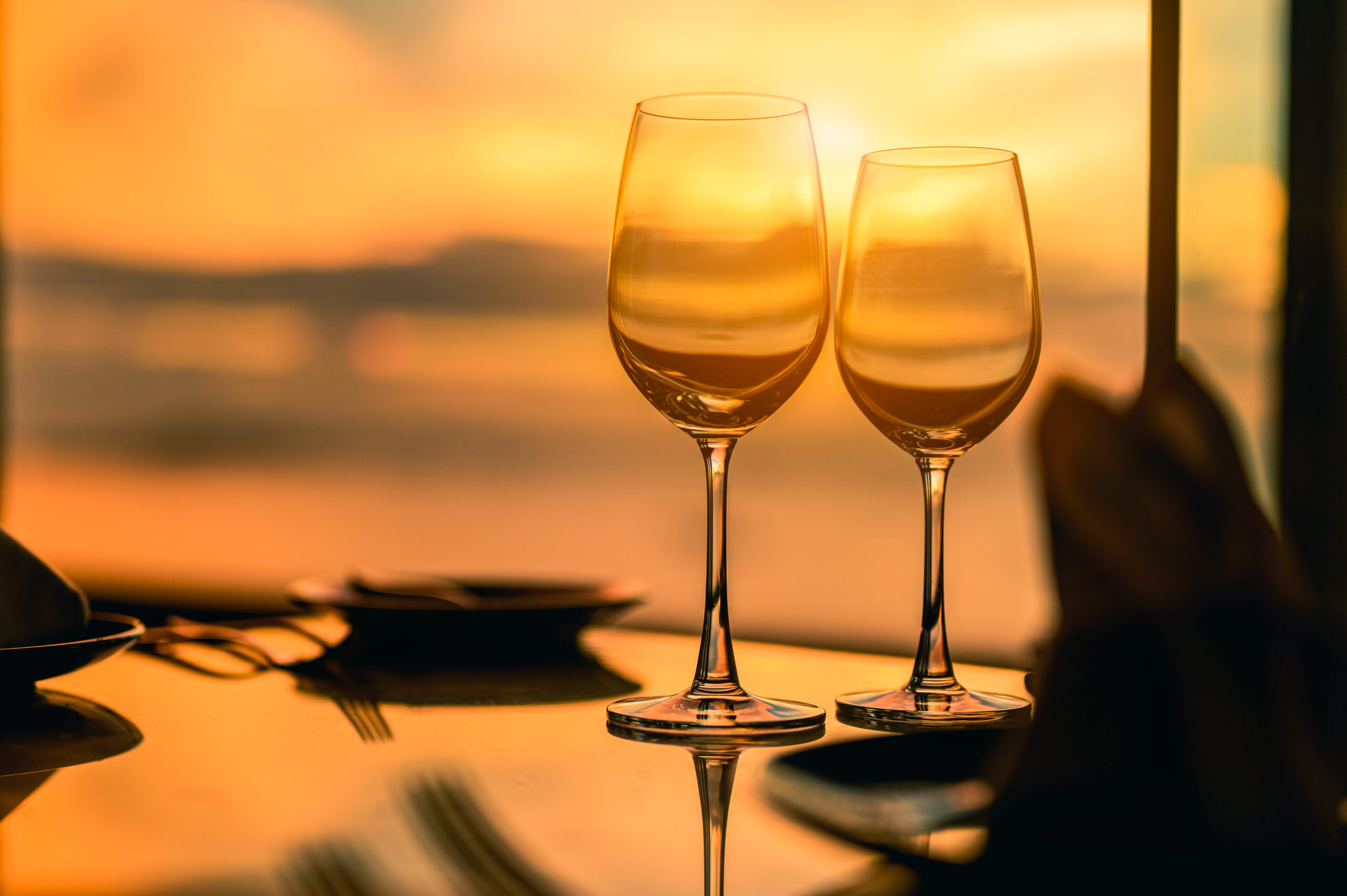 Two crystal wine glasses glowing at sunset overlooking the Mediterranean on a luxury French Riviera tour, France