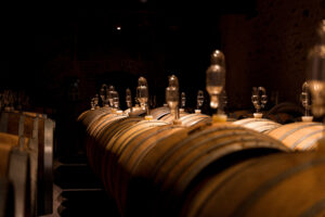 Oak wine barrels with glass airlocks fermenting in a dark Loire Valley wine cellar on a luxury wine tour, France