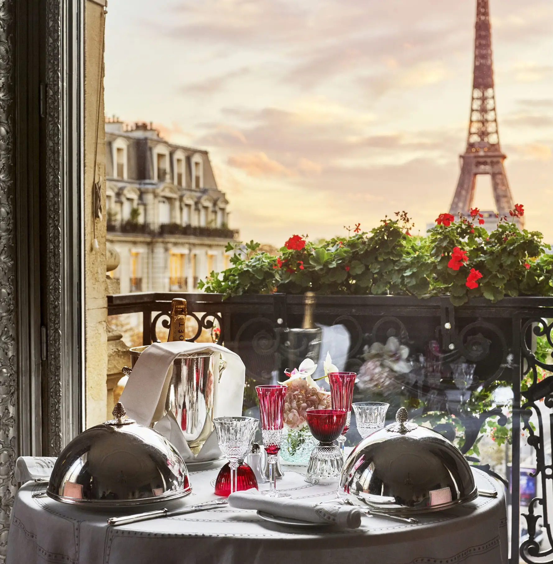 Romantic private dinner table with silver cloches and red crystal glasses overlooking the Eiffel Tower at sunset, Paris, France