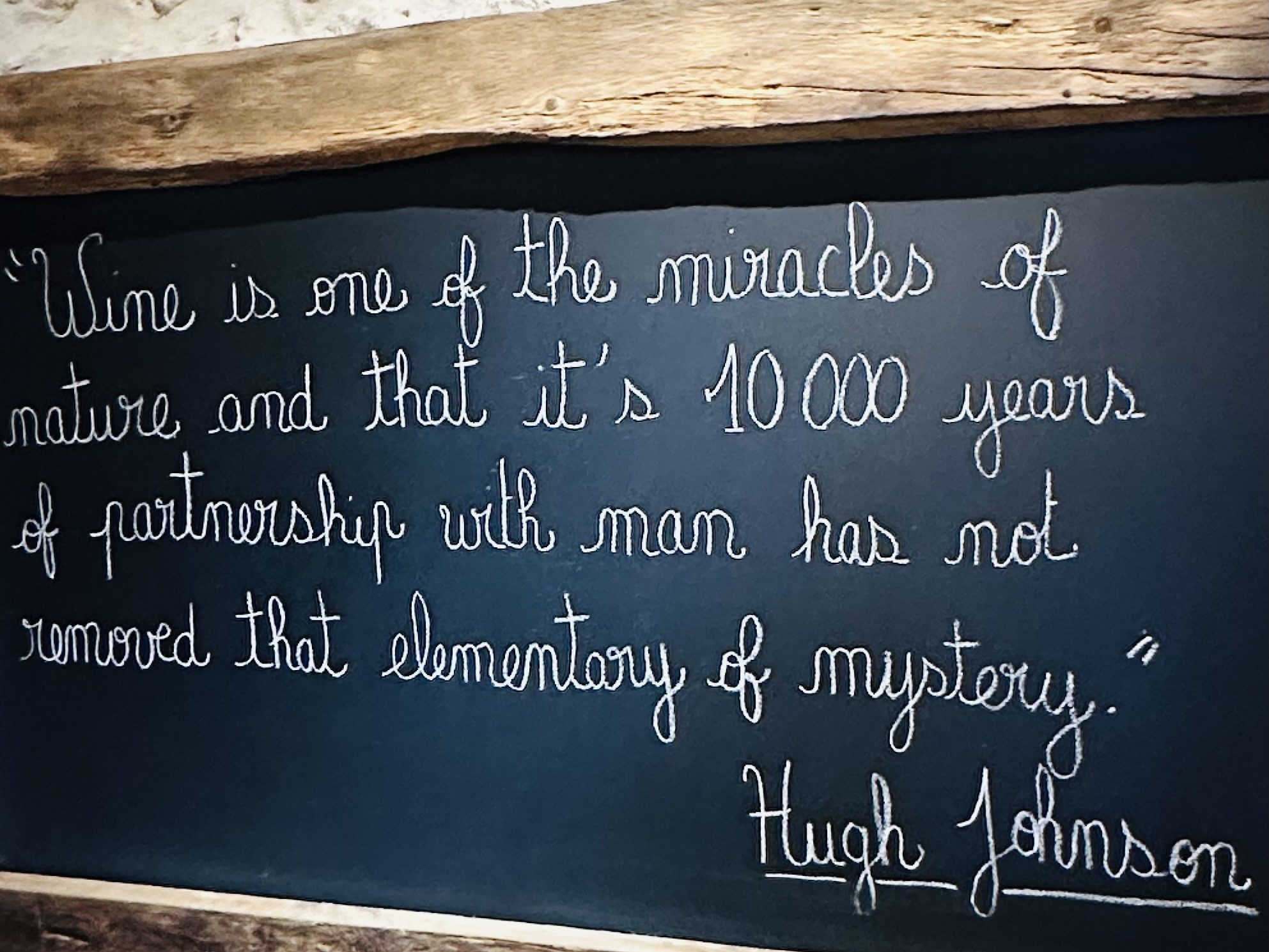 Handwritten Hugh Johnson wine quote on a chalkboard at a Bordeaux wine cellar during a luxury wine tour, France